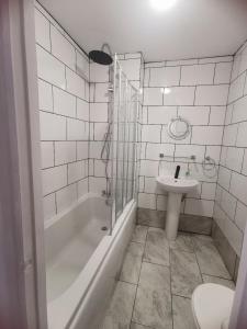 a bathroom with a sink and a tub and a toilet at Cavendish House Hotel in Great Yarmouth