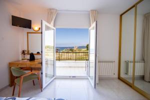 a room with a desk and a view of a balcony at Hotel Paraimo in A Lanzada