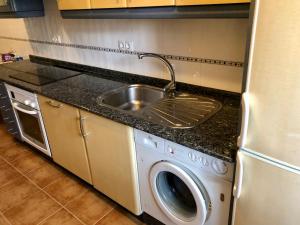 a kitchen with a sink and a washing machine at Apartamento Ribeira Sacra in Monforte de Lemos +3 photos