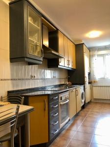uma cozinha com armários castanhos, uma mesa e um lavatório em Vivenda da Avoa em Monforte de Lemos