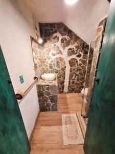baño con pared de piedra y lavamanos en Apartamento frente al mar con jardín privado, en Puebloviejo