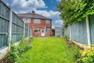 a backyard with a fence and a brick house at Modern 3 Bedroom 2 Bath House with Parking by 360Midlands Wednesbury, Birmingham in Birmingham