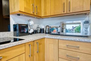 a kitchen with wooden cabinets and a counter top at Modern 3 Bedroom 2 Bath House with Parking by 360Midlands Wednesbury, Birmingham in Birmingham