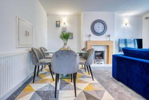 uma sala de jantar com mesa e cadeiras e um relógio em Modern 3 Bedroom 2 Bath House with Parking by 360Midlands Wednesbury, Birmingham em Birmingham
