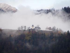 a house on top of a hill in the fog at Tony's Old Farm in Begunje na Gorenjskem