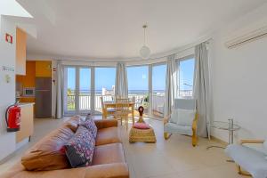 een woonkamer met een bank en uitzicht op de oceaan bij Penthouse Quilha in Fuzeta