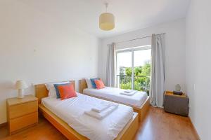 twee bedden in een kamer met een raam bij Penthouse Quilha in Fuzeta +27 foto's
