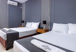 um quarto de hotel com duas camas com lençóis brancos em Hotel Taurus em Piura