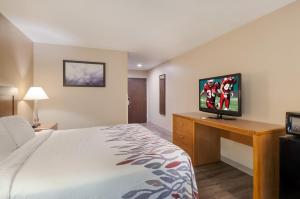 a hotel room with a bed and a flat screen tv at Red Roof Inn Dahlgren - Naval Base in Dahlgren