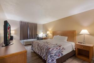a hotel room with a bed and a flat screen tv at Red Roof Inn Dahlgren - Naval Base in Dahlgren