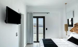 - une chambre avec un lit et une télévision à écran plat dans l'établissement BLACK AND WHITE VILLAS FTELIA - MYKONOS, à Mykonos