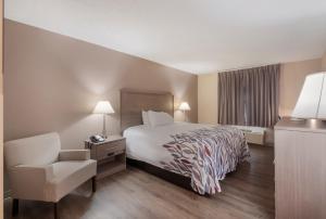 a hotel room with a bed and a chair at Red Roof Inn Dahlgren - Naval Base in Dahlgren