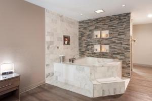 a bathroom with a tub and a stone wall at Red Roof Inn Dahlgren - Naval Base in Dahlgren
