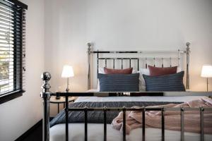 1 dormitorio con cama de metal y almohadas en Cricklewood- 2 bedroom enchanting miner's cottage, en Daylesford