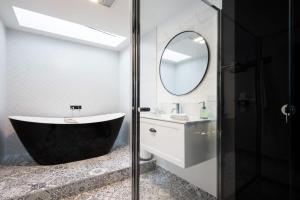 Un baño con bañera, lavabo y espejo. en Cricklewood- 2 bedroom enchanting miner's cottage, en Daylesford 11 fotos más