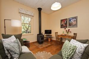 a living room with a couch and a stove at Quince Cottage - scenic escape with spa in Daylesford
