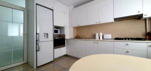 a kitchen with white cabinets and a table in it at Between Parks - King Bed - Central - Football field in Bucharest