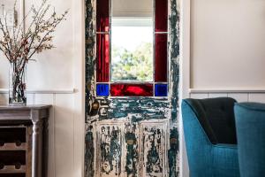 a door with a window and a blue chair at Table Hill Cottage in Daylesford