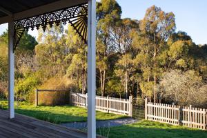 a wooden porch with a fence and trees at Table Hill Cottage in Daylesford