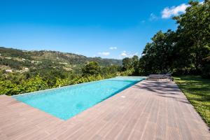 a swimming pool with a wooden deck next to trees at Douro Senses - Nature House in Cinfães