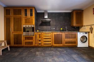 a kitchen with wooden cabinets and a washing machine at Douro Senses - Nature House in Cinfães
