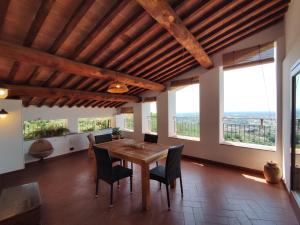 a dining room with a table and chairs and windows at La terrazza di Elas a Uzzano in Uzzano