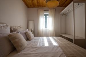 a bedroom with a large white bed with a window at Douro Senses - Village House in Cinfães