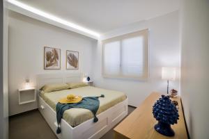 a white bedroom with a bed and a table at Casa Blanca Sea View in Marina di Ragusa