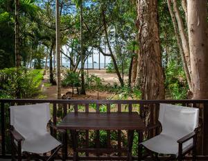 a wooden table and two chairs next to a tree at Kewarra Beach Resort in Kewarra Beach