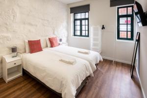 a bedroom with two beds with white sheets and red pillows at Entire House with 4 Master Suites & Backyard - Central Location in Vila Nova de Gaia