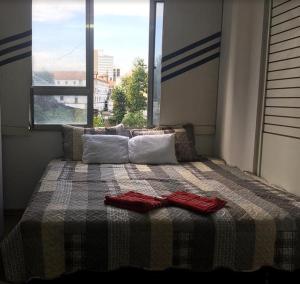 - un lit avec 2 serviettes rouges et une fenêtre dans l'établissement Meu Apartamento a 15min de Copacabana, à Rio de Janeiro