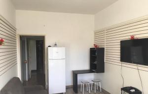 a living room with a refrigerator and a tv on a wall at Meu Apartamento a 15min de Copacabana in Rio de Janeiro