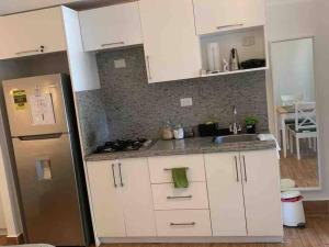 a kitchen with white cabinets and a stainless steel refrigerator at Espectacular Apartamento En Tanama Cap Cana in Punta Cana