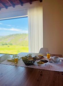 einen Tisch mit Speisen und Getränken auf einem Tisch mit Fenster in der Unterkunft Casa do Afonso in Brufe