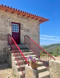 a stone house with a red door and stairs at Casa do Afonso in Brufe