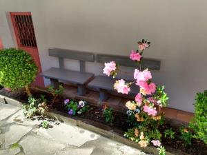 una panchina blu con fiori rosa di fronte a un edificio di Apartamentos Aromas de Gramado - Bairro Centro a Gramado