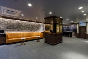 a waiting room with a couch and a bar at Via Inn Shimonoseki in Shimonoseki