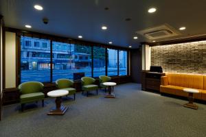 a waiting room with a yellow couch and green chairs at Via Inn Shimonoseki in Shimonoseki
