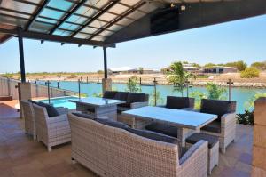 eine Terrasse mit Tischen und Stühlen sowie einem Pool in der Unterkunft 27 Corella Court in Exmouth