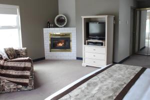 a living room with a fireplace and a television at Quarterdeck Inn Port Hardy in Port Hardy