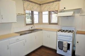 a white kitchen with a stove and a sink at 10 Tautog Street in Exmouth