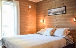 a bedroom with wooden walls and a bed with pillows at Beautiful Home In Skare With 3 Bedrooms in Lii