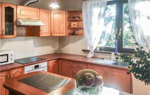 una cocina con armarios de madera y un bol de fruta en una mesa en Lovely Home In Swietajno With Kitchen en Świętajno