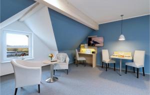 ダゲビュルにあるLovely Apartment In Dagebll With Kitchenの青い壁の客室で、椅子とテーブルが備わります。