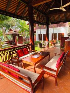 a patio with couches and tables on a porch at Luang Prabang Villa Sirikili River View in Luang Prabang