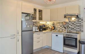 a kitchen with a refrigerator and a stove top oven at Amazing Home In Hermanville-Sur-Mer in Hermanville-sur-Mer