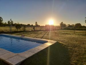 a sunset over a field with a swimming pool at AYRES DE BRANDSEN in Brandsen