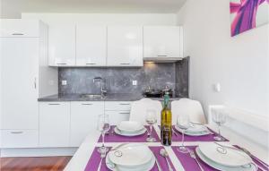 uma cozinha branca com uma mesa com pratos e copos de vinho em Lovely Apartment In Malinska With Wifi em Malinska
