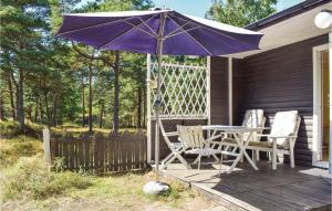 einen lila Regenschirm und zwei Stühle und einen Tisch auf der Veranda in der Unterkunft 2 Bedroom Stunning Home In Lderup in Löderup