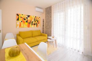 a living room with a yellow couch and a table at Lovely apartment Lungomare in Vlorë